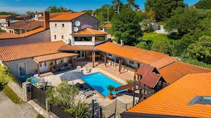 A residential property with a swimming pool, stone walls, and a covered patio area.
