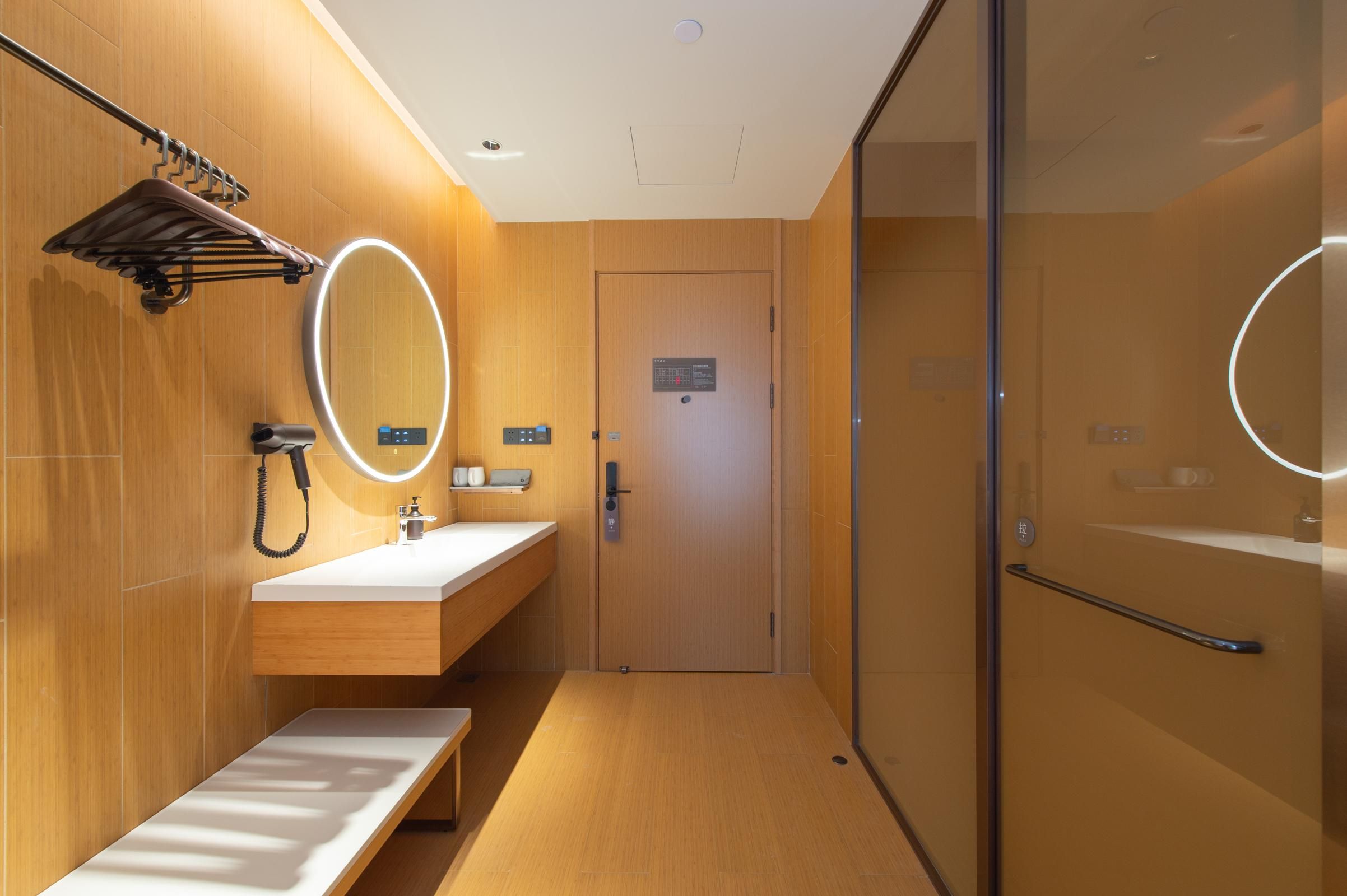 A modern bathroom with a wooden vanity, a mirror, a towel rack, and a glass shower enclosure.