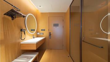 A modern bathroom with a wooden vanity, a mirror, a towel rack, and a glass shower enclosure.