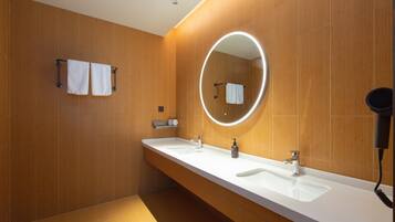 A modern bathroom with wooden walls, a large mirror, and two sinks.