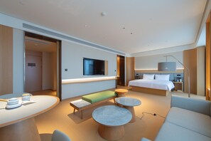 Quarto de hotel moderno com cama, área de estar e televisão.