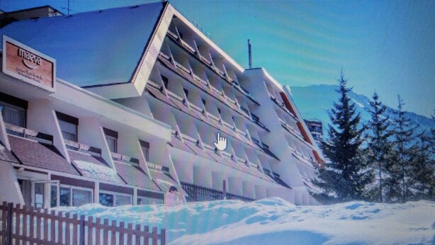 A building with a sloped roof, a sign on the side, and a snowy landscape with trees. - SKI IN THE SUN: February 16 to 23, 2025, Serre Chevalier Chantemerle club Maeva (Saint-Chaffrey)