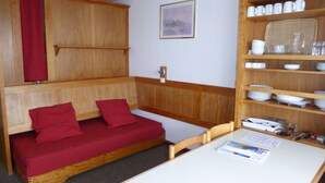 A compact room with a wooden bunk bed, a small table, and shelves with dishes and glasses. - SKI IN THE SUN: February 16 to 23, 2025, Serre Chevalier Chantemerle club Maeva (Saint-Chaffrey)