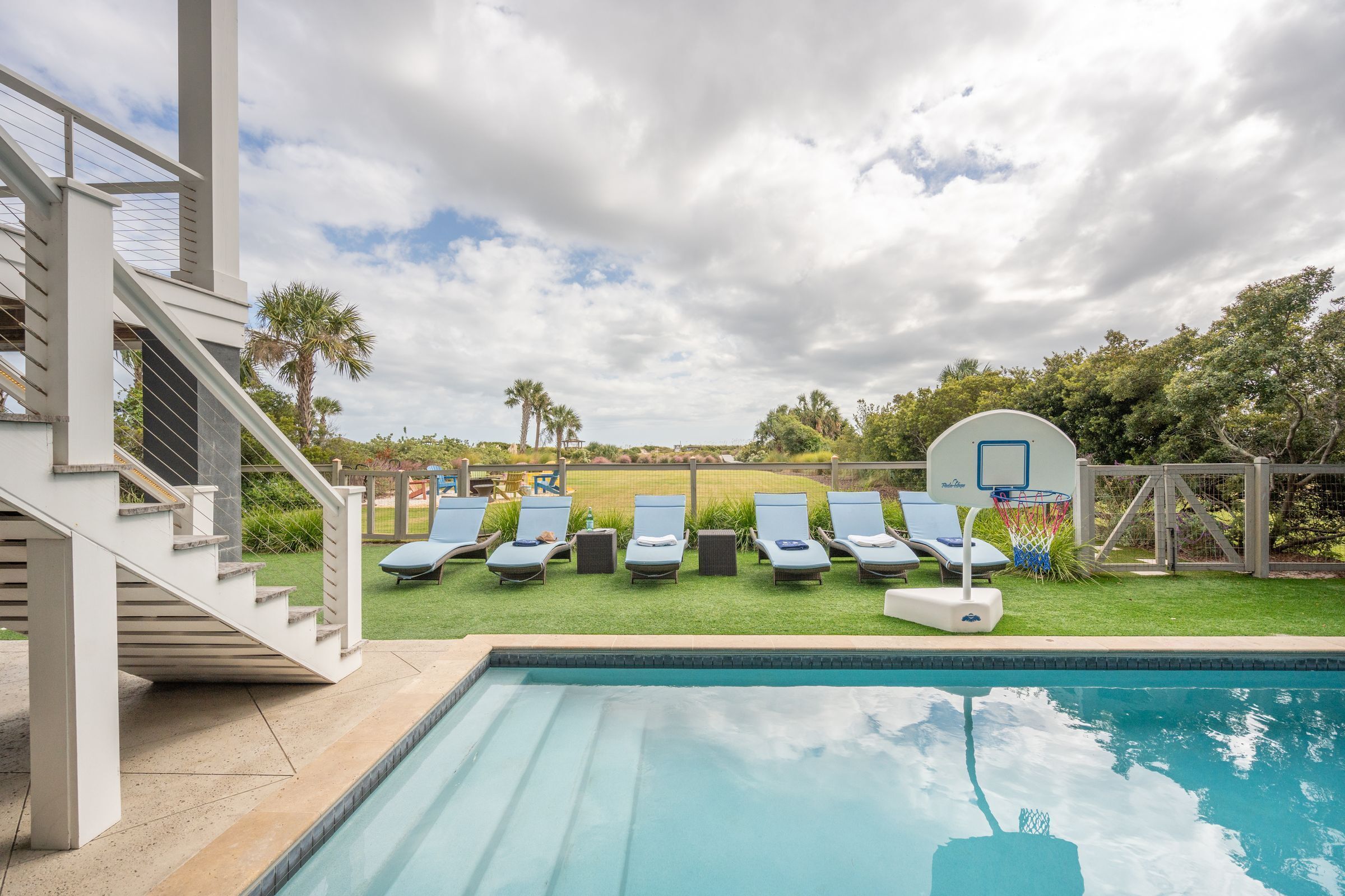 A swimming pool with lounge chairs and a basketball hoop.