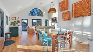 A spacious dining area with a wooden table and chairs, large windows, and a view of the outdoors. - Woodhaven on Pleasant Lake |Pleasant Lake |Lakefront |Wraparound Deck |Views |Dock |Kayaks & Boards (East Troy)