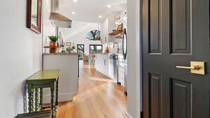 A modern kitchen with white cabinets, a stainless steel range hood, and a wooden floor. - Woodhaven on Pleasant Lake |Pleasant Lake |Lakefront |Wraparound Deck |Views |Dock |Kayaks & Boards (East Troy)