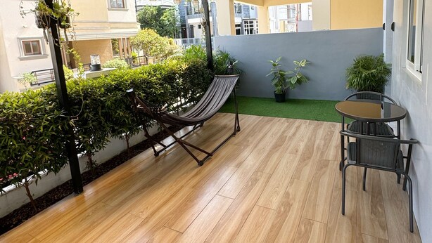 A covered patio with a hammock, a small table, and chairs. - 2BR Home (corner lot). With Lanai, 100 Mbps Internet and Netflix. (Balanga)