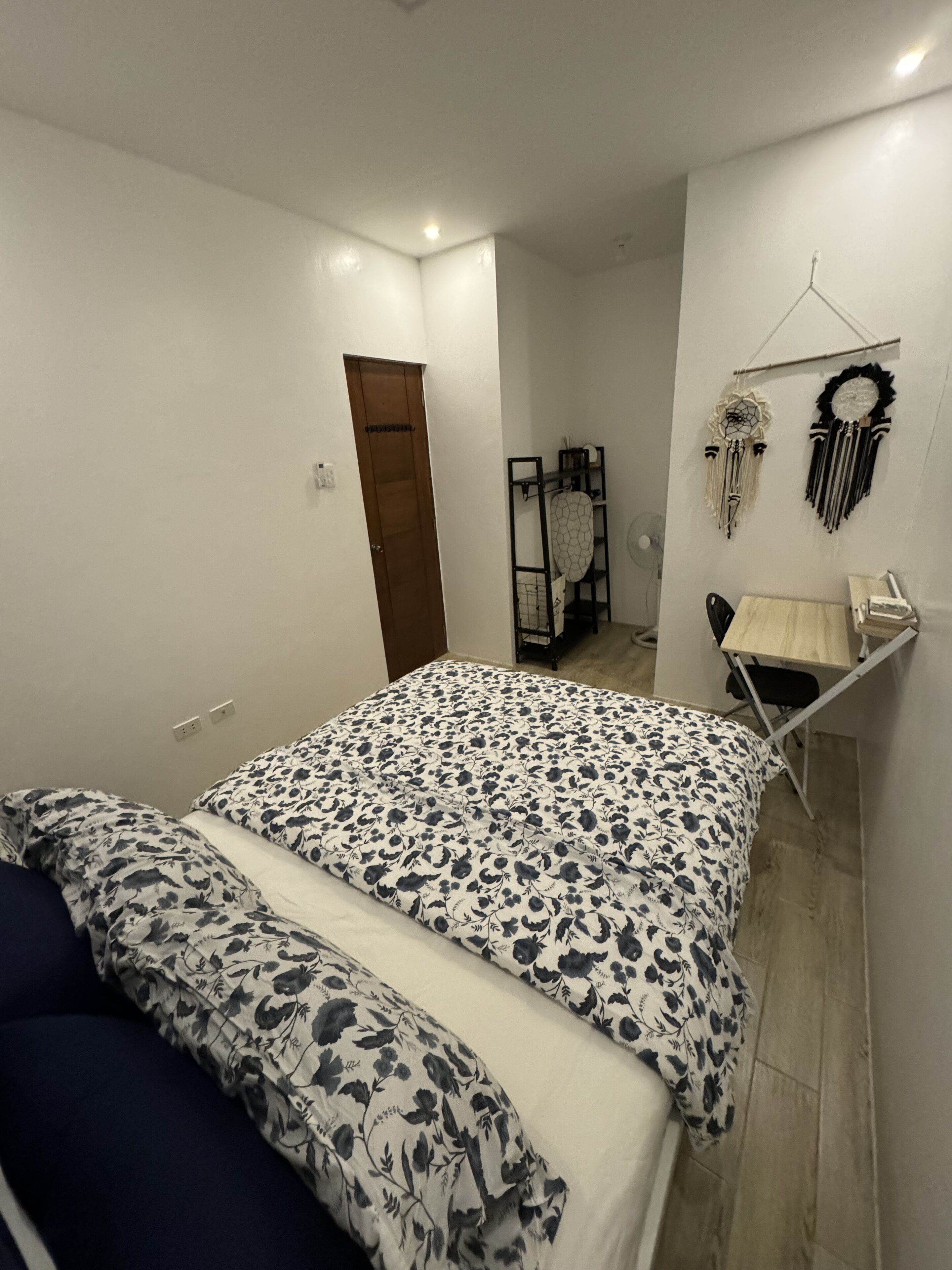 A bedroom with a bed, a desk, and a wardrobe.