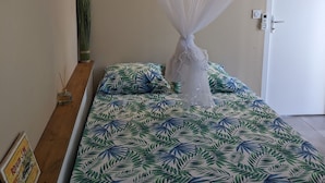 A bedroom with a canopy bed, a bedside table with a lamp, and a door with a lock.