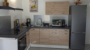 A modern kitchen with wooden cabinets, a stainless steel refrigerator, a coffee maker, and a microwave.