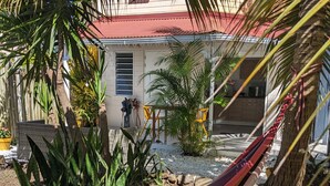 A hammock in a garden with a house in the background.