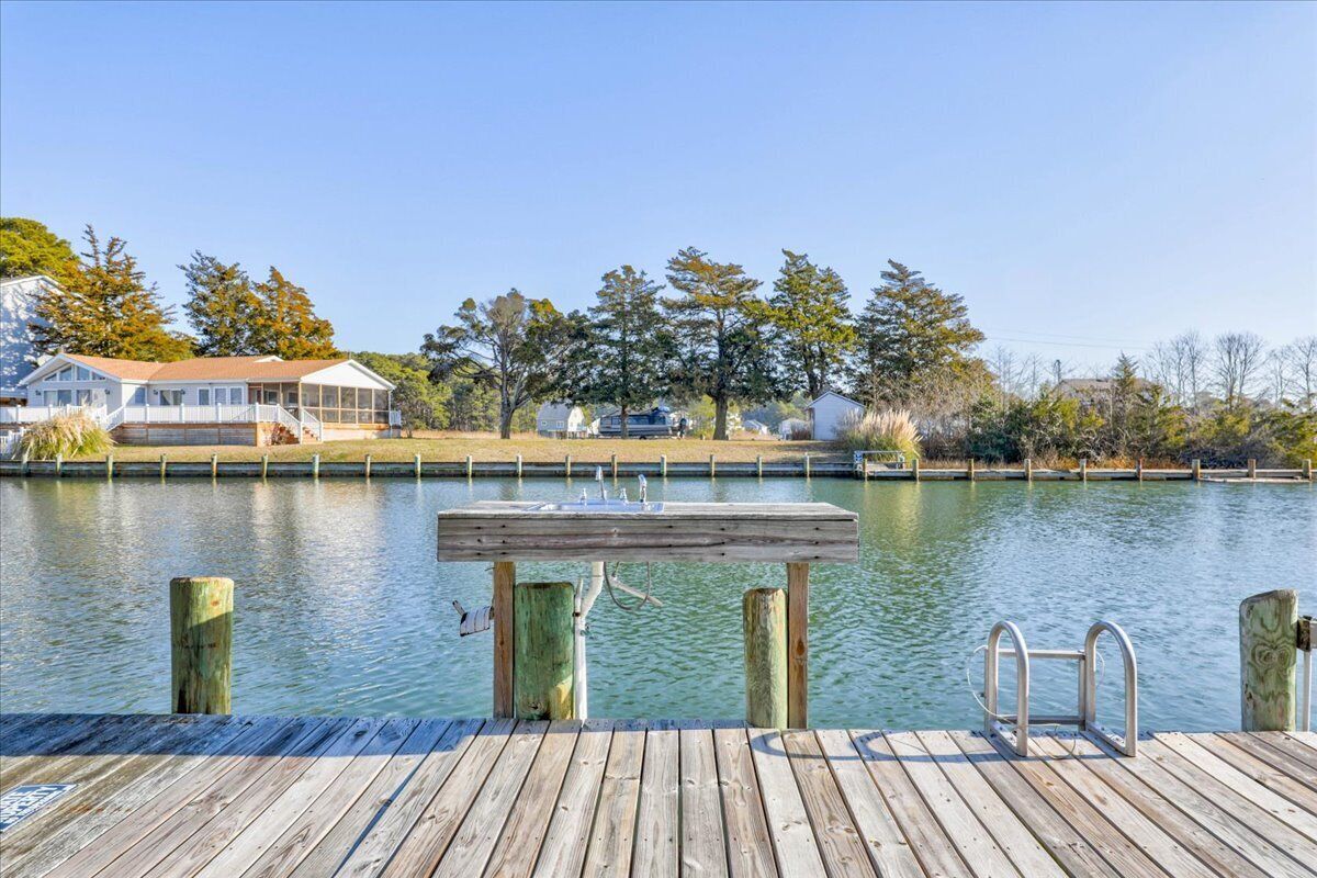 A wooden dock extending into a calm body of water with a clear sky above.