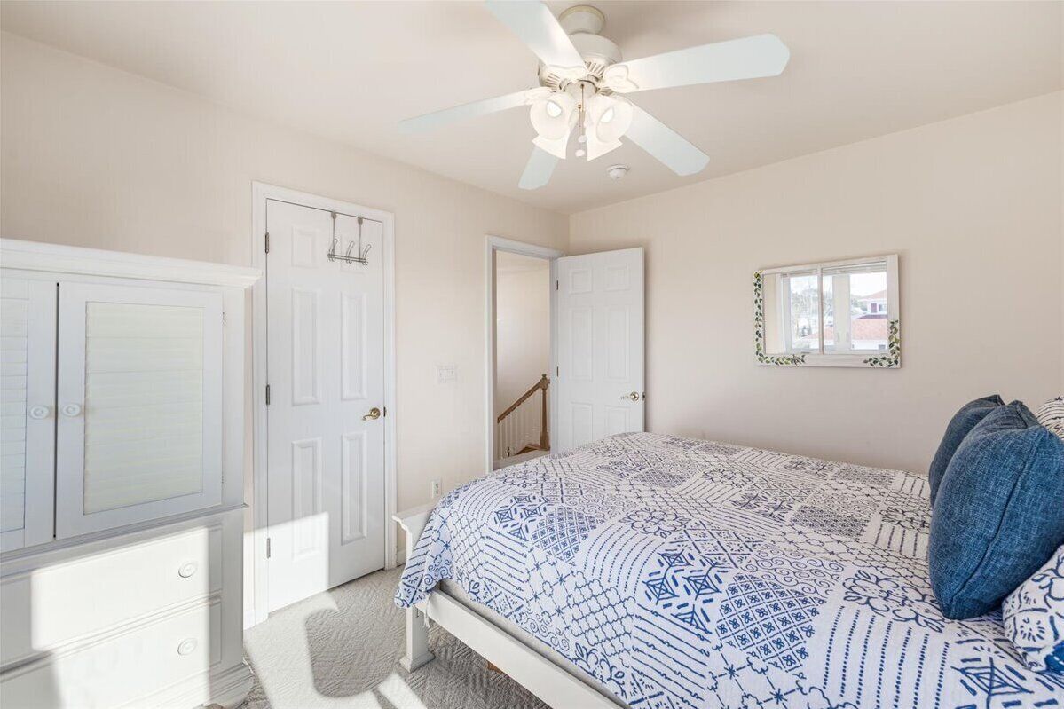 A bedroom with a bed, a ceiling fan, a window, and a door.