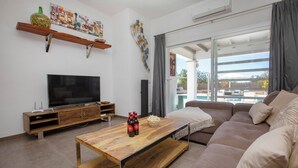 Una sala de estar moderna con un televisor de pantalla plana, una mesa de centro de madera y un sofá.