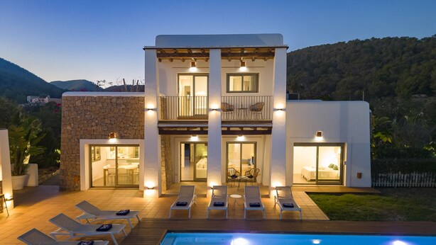 A modern two-story house with a swimming pool, outdoor seating, and a balcony.