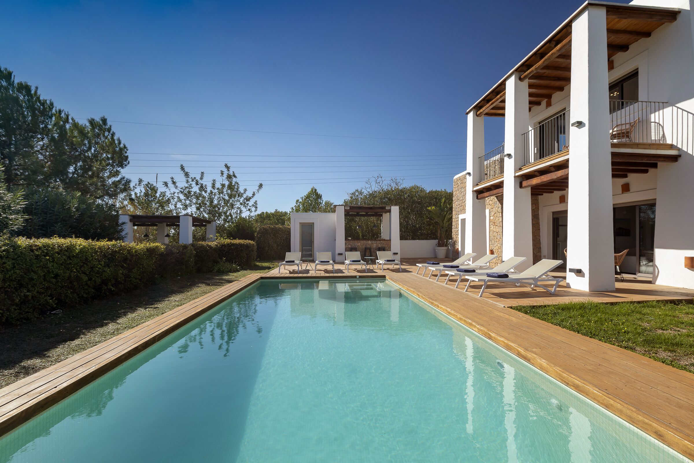 A modern pool area with lounge chairs and a wooden deck.