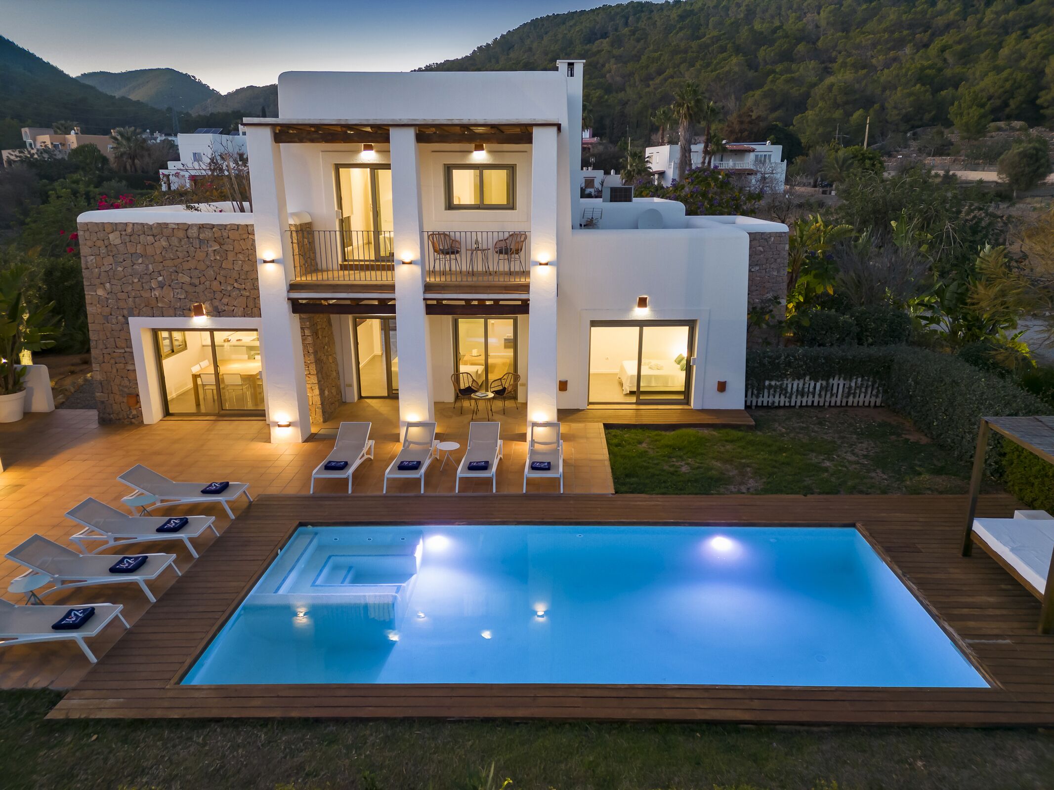 Une maison moderne à deux étages, dotée d’une piscine, d’un espace de détente extérieur et offrant une vue sur les collines environnantes.