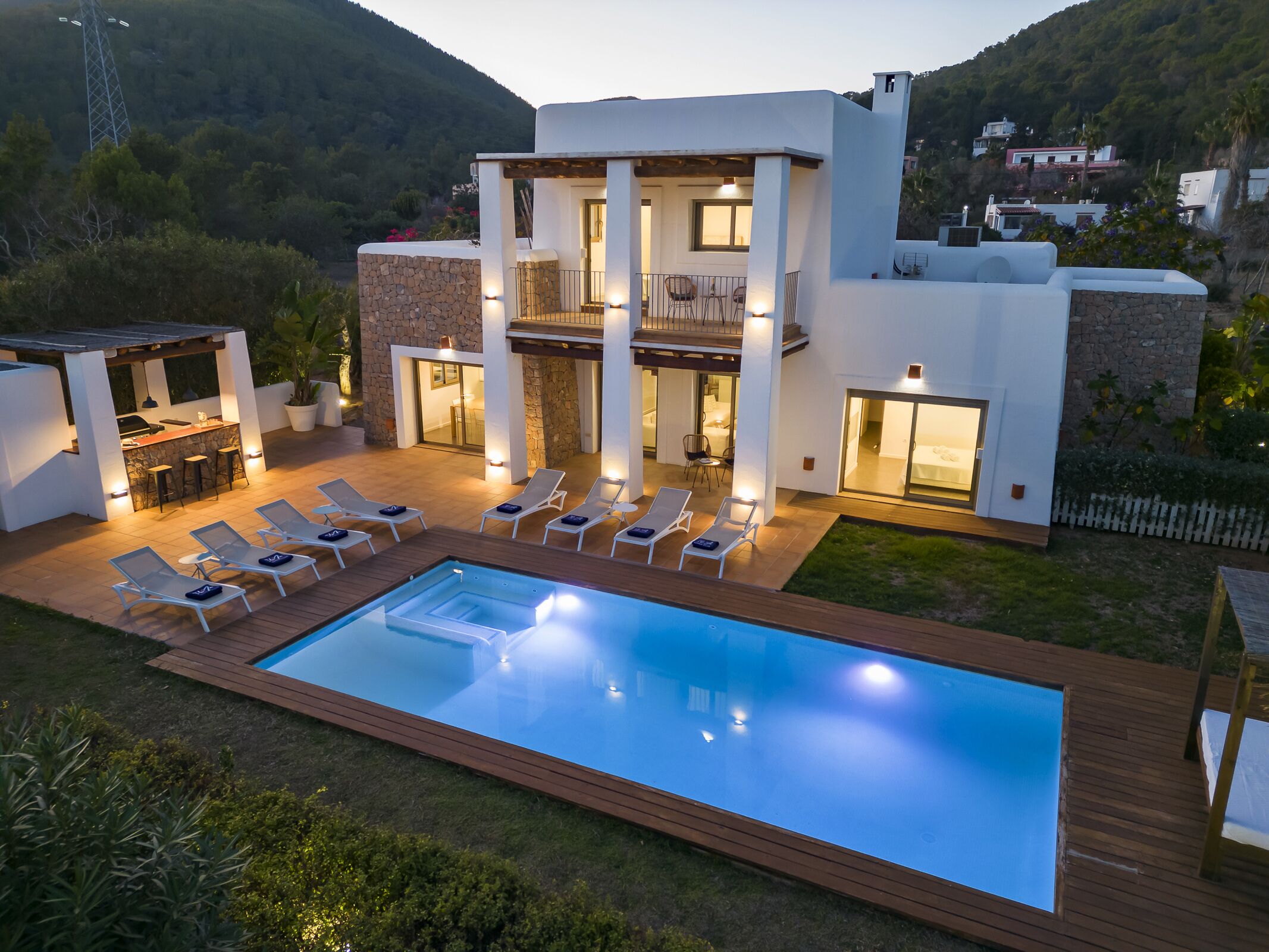 Une maison moderne à deux étages dotée d’une piscine, d’un espace salon extérieur et d’un coin barbecue.
