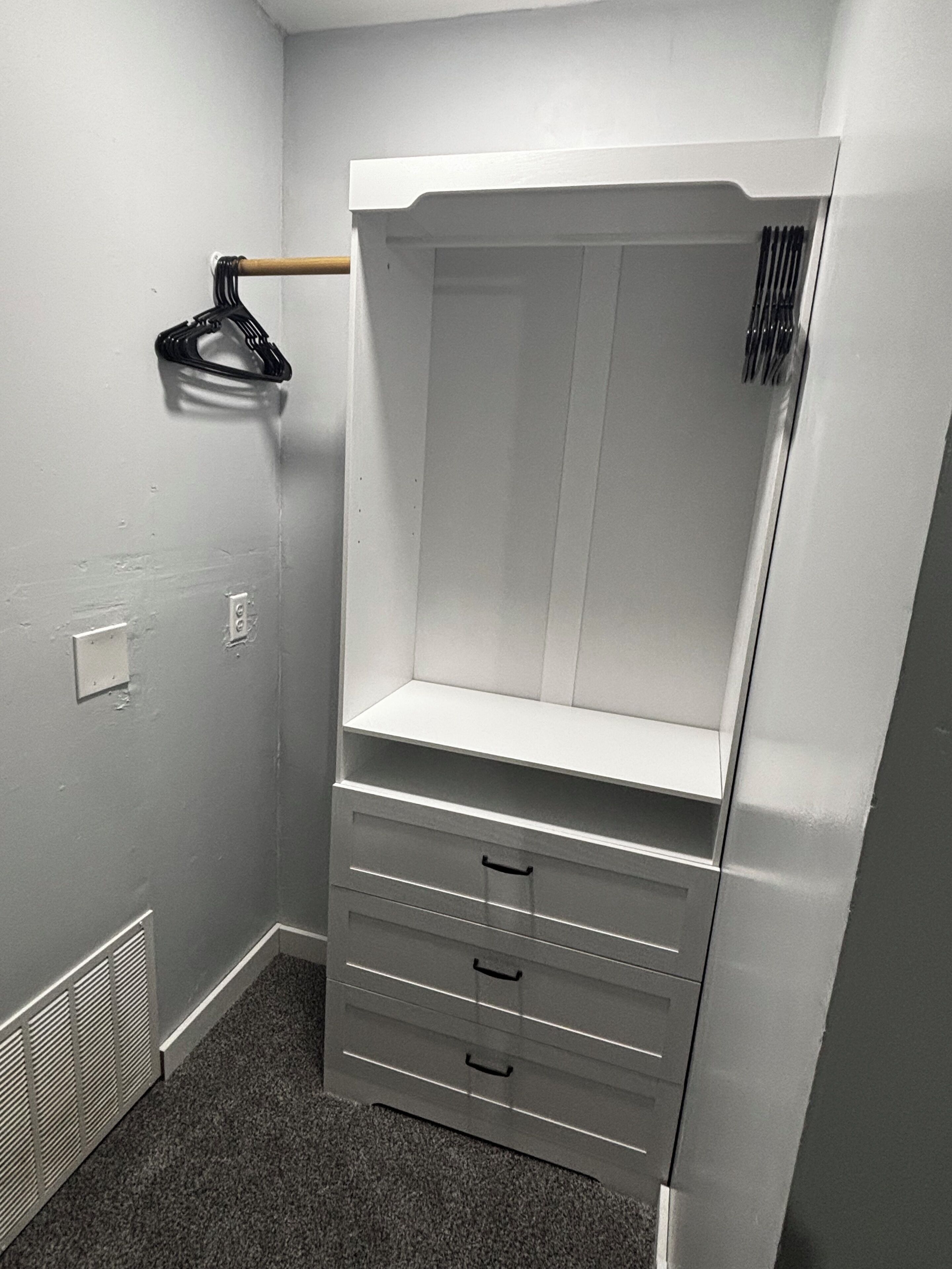 Ein begehbarer Kleiderschrank mit beschichteter Kleiderstange, einer Kleiderhängung und einem eingebauten Regal.