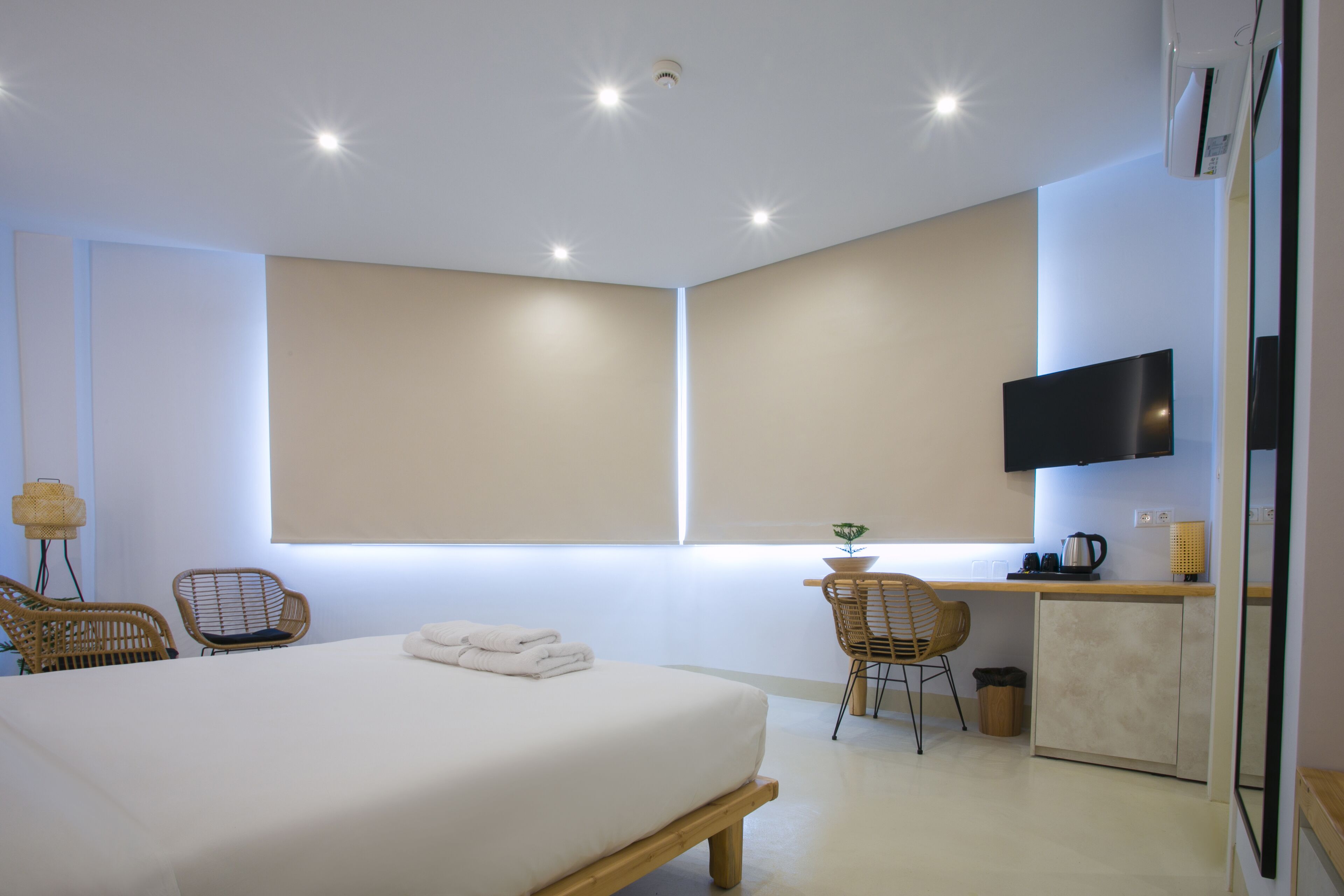 Habitación de hotel moderna con una cama grande, un escritorio con silla, televisión y ventana con luz natural.