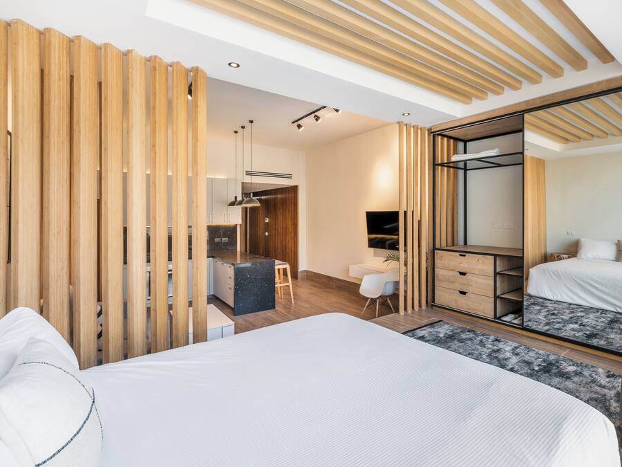 A modern bedroom with a large bed, a desk, and a wardrobe.