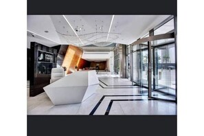 Experience the sleek, contemporary lobby at Sparkle Towers, featuring a central reception area and comfortable seating.