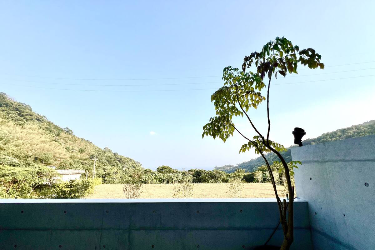 A potted plant on a balcony with a view of a hilly landscape.