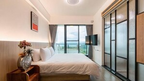 A hotel room with a bed, a TV, a window with a view, and a decorative vase. - Chance Villa 261 (Toucheng)