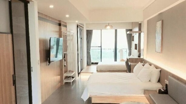A modern hotel room with a large bed, a TV, a small table, and a view of the outdoors. - Chance Villa 261 (Toucheng)