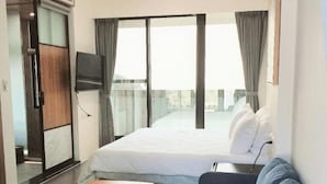 A hotel room with a bed, a sofa, a wooden table, a TV, and a balcony with curtains. - Chance Villa 261 (Toucheng)