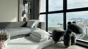A modern bedroom with a large bed, a view of the city, and a unique stuffed animal decoration.