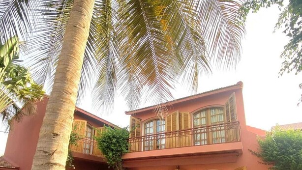 A two-story building with a balcony, large windows, and a well-maintained lawn. - Les Goréennes Suites (Mbour)