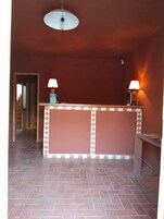 A reception area with a tiled floor, a reception desk, two wall-mounted lamps, and a ceiling light fixture.