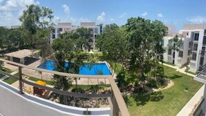 Un complejo residencial con piscina rodeado de vegetación y edificios modernos.