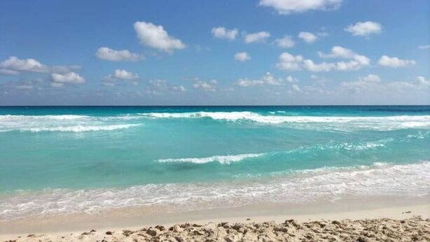 Una playa con aguas turquesas cristalinas y una orilla arenosa.