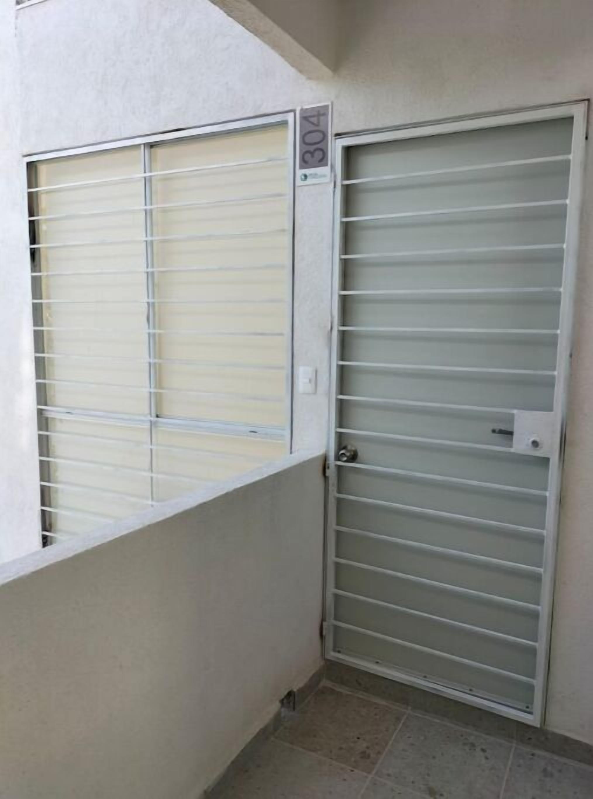 Ein verschlossenes Metalltor mit Nummernschild '304' und einem Fenster mit horizontalen Rollläden.