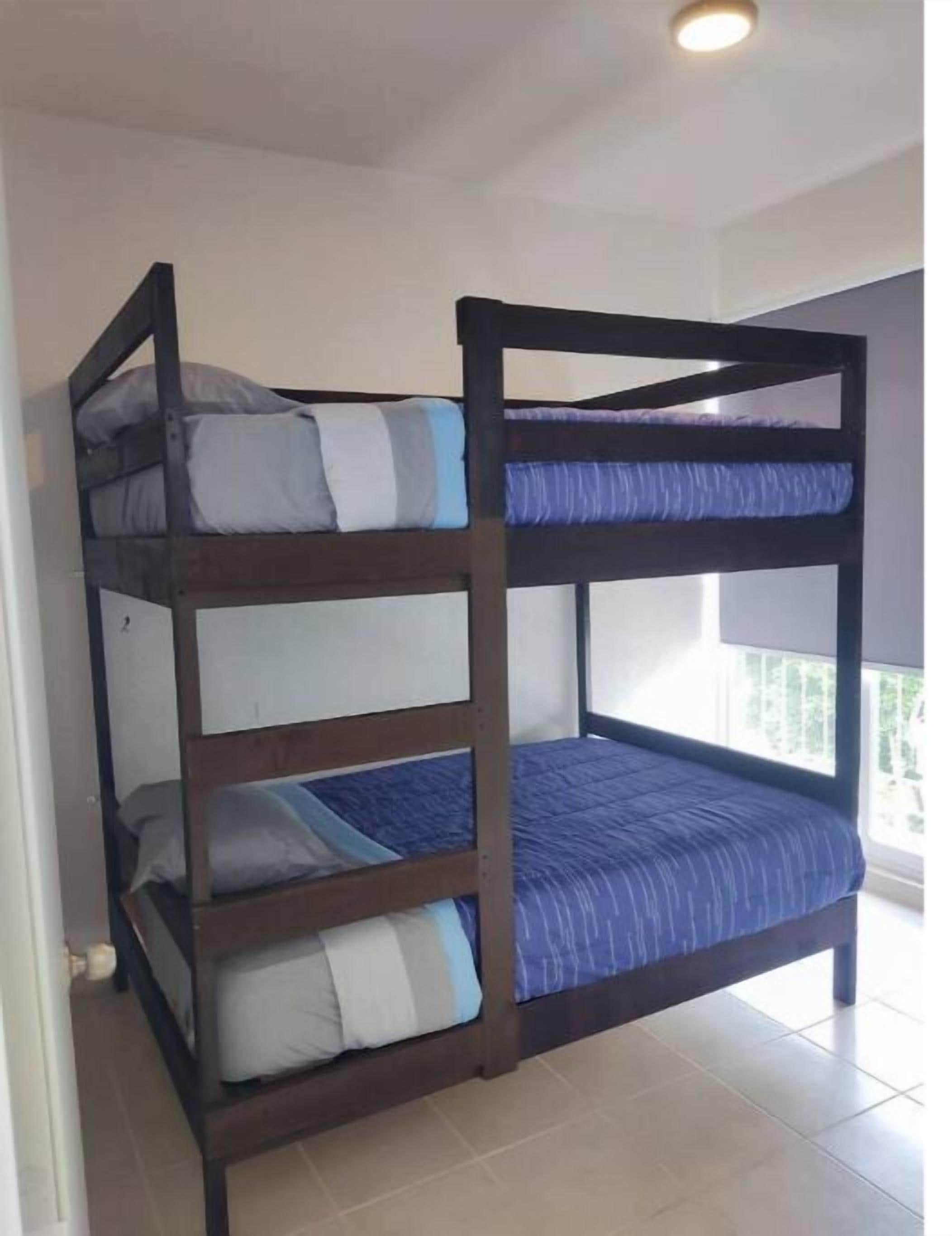 A bunk bed with four levels, each with a pillow and a blue blanket.