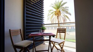 A balcony with two wooden chairs, a small table, and a potted plant. - Alojamento Santa Maria B4 1E (Tavira)