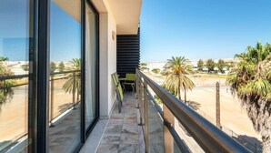A balcony with a view of palm trees and a beach.