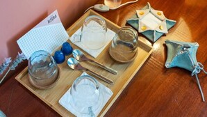 Una bandeja de madera con cristalería, una cuchara, una servilleta y una pequeña bolsa azul sobre una mesa de madera.