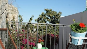 En balkon med gelænder, et grønt bord og plantekasser.