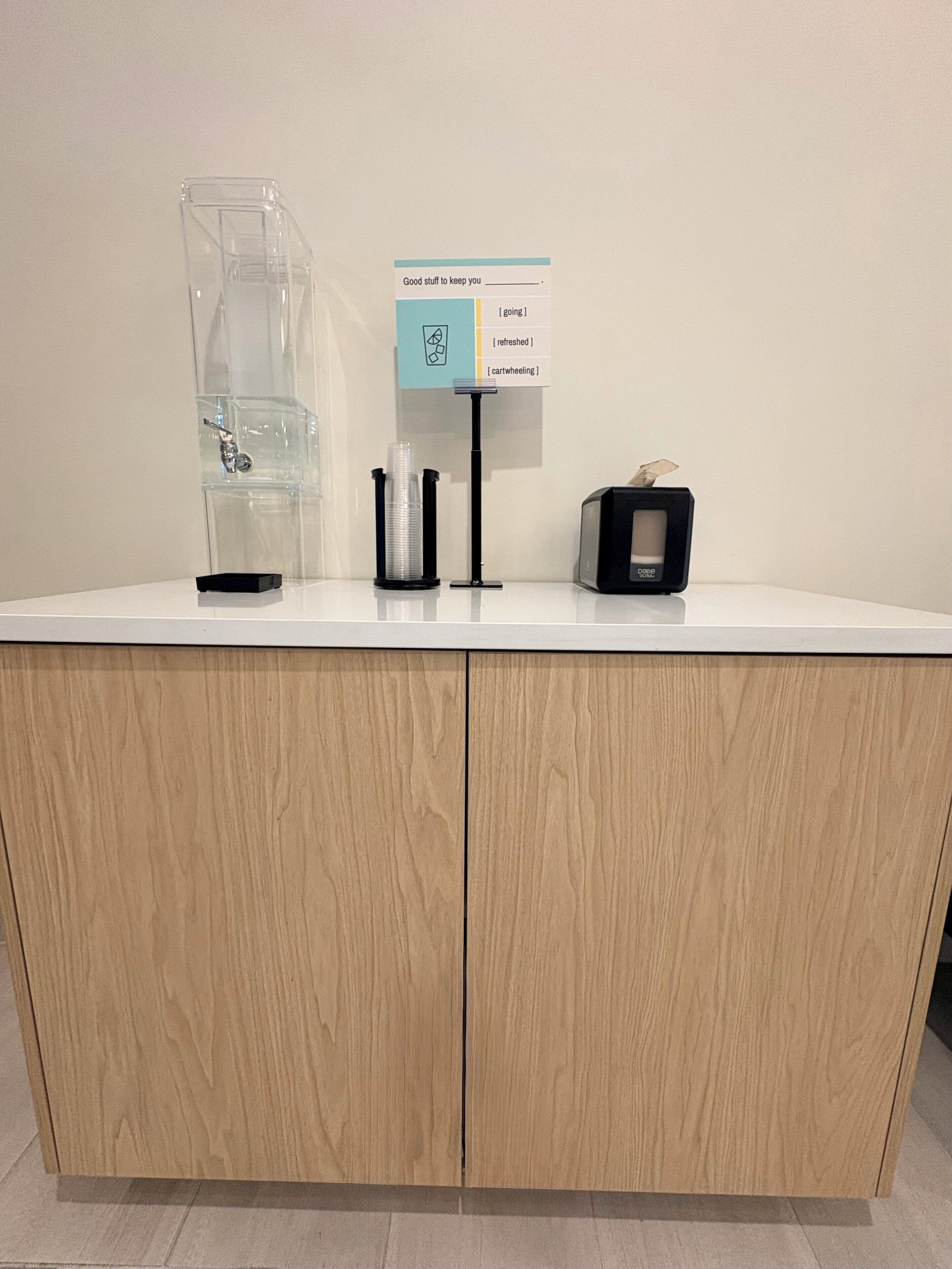 A counter with a coffee machine, a water dispenser, and a tissue box.