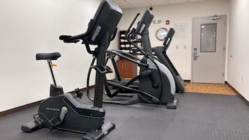 A fitness room with two treadmills, a stationary bike, and a mat.