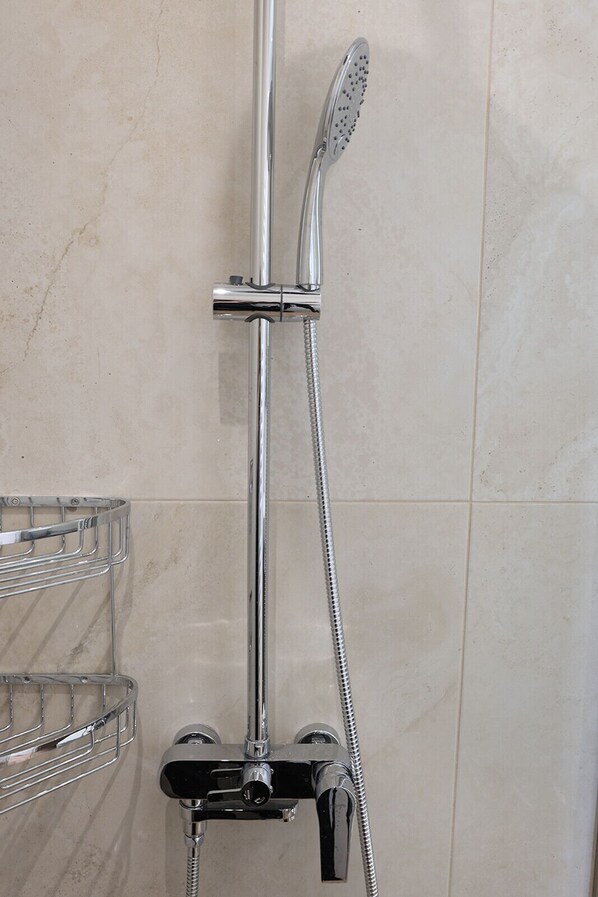 A shower with a handheld showerhead and a wall-mounted faucet. - LIV - View and the City Studio in Athens (Athens)