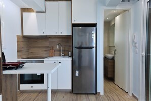A modern kitchen with white cabinets, a stainless steel refrigerator, and a wooden countertop. - LIV - View and the City Studio in Athens (Athens)
