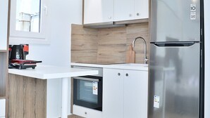 Une cuisine moderne avec des armoires blanches, un réfrigérateur en acier inoxydable et un four encastré.