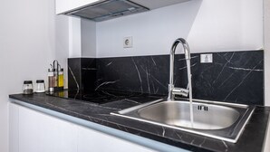 A kitchen with a black marble backsplash, stainless steel sink, and a range hood.