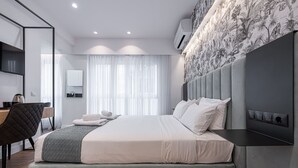 A modern bedroom with a bed, bedside table, and a desk area with a chair.