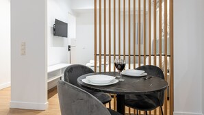Un comedor moderno con una mesa redonda, sillas negras y una copa de vino tinto.