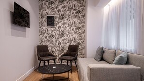 Ein modernes Wohnzimmer mit einem grauen Sofa, zwei braunen Sesseln und einem schwarzen Couchtisch.